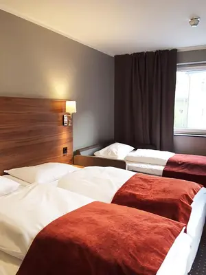 a hotel room with three beds and a window at Thon Hotel Otta in Otta
