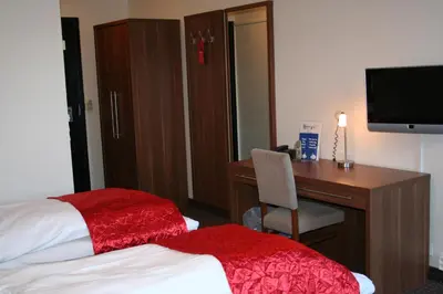 a hotel room with a desk and a bed with a red blanket at Thon Hotel Otta in Otta
