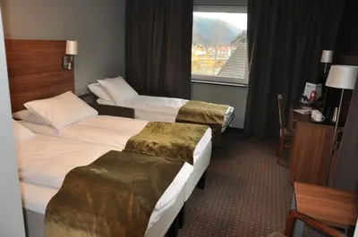a hotel room with three beds and a window at Thon Hotel Otta in Otta