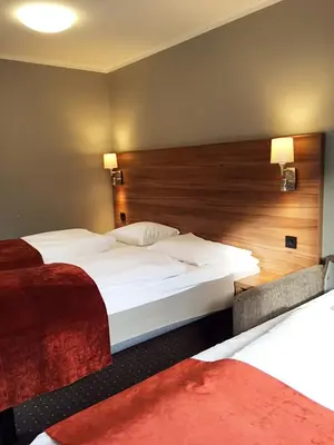 a hotel room with two beds and a wooden headboard at Thon Hotel Otta in Otta