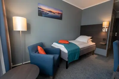 a small room with a bed and a blue chair at Thon Hotel Måløy in Måløy