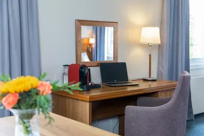 a hotel room with a desk with a laptop and a mirror at Thon Hotel Backlund in Levanger