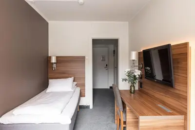 a bedroom with two beds and a flat screen tv at Thon Hotel Backlund in Levanger