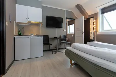a hotel room with a bed and a kitchen with a table at Pensjonat Jarlen in Trondheim