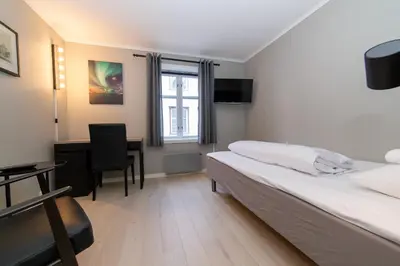 a hotel room with a bed and a desk at Pensjonat Jarlen in Trondheim