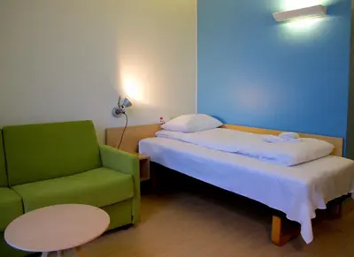 a bedroom with a bed and a green chair at Hotel St. Olav in Trondheim