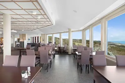 a dining room with tables and chairs and windows at Stav Hotel in Malvik