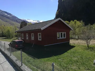 a red house with a car parked in front of it at Steinshølen Holiday Home in Flåm