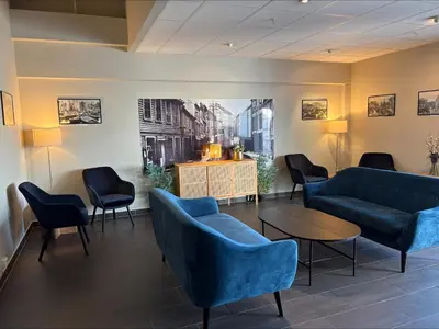 a waiting room with blue couches and a table and chairs at Thon Hotel Baronen in Ålesund