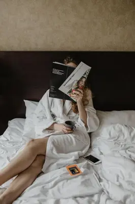 a woman laying in bed reading a book at Comfort Hotel Park in Trondheim