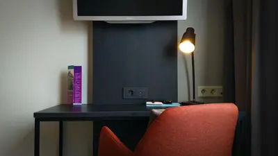 a room with a desk with a red chair and a tv at Quality Hotel Augustin in Trondheim