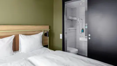 a bedroom with a bed and a bathroom with a shower at Comfort Hotel Trondheim in Trondheim