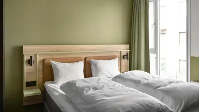 a bed with white sheets and pillows next to a window at Comfort Hotel Trondheim in Trondheim