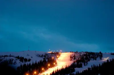 a snowy road with street lights at night at Kvitfjell Hotel Kvitfjellvegen 492 in Kvitfjell