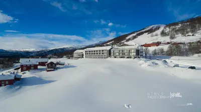 a ski lodge in the snow with mountains in the background at Ustedalen Hotel Geilo in Geilo