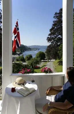 a woman sitting at a table looking out a window at Fjordslottet Hotel in Fotlandsvåg