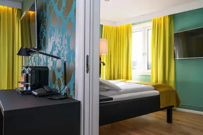a bedroom with a bed with yellow curtains and a desk at Thon Hotel Nidaros in Trondheim