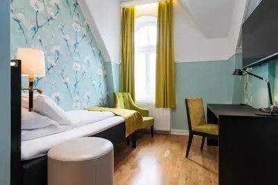 a bedroom with a bed and a desk and a window at Thon Hotel Nidaros in Trondheim