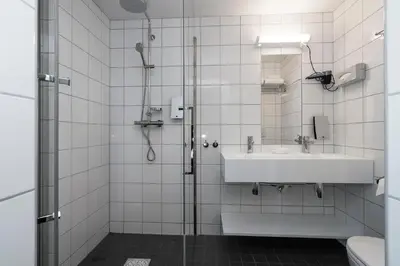 a white bathroom with a sink and a shower at Thon Hotel Nidaros in Trondheim