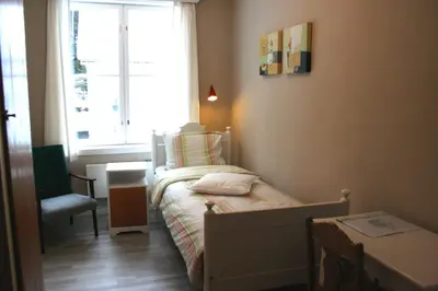 a small bedroom with a bed and a window at Furulund Pensjonat in Ron