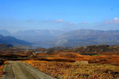 a dirt road in the middle of a field with mountains at Furulund Pensjonat in Ron