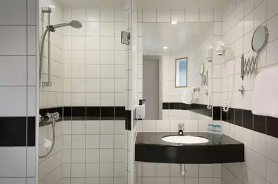 a white tiled bathroom with a sink and a shower at Scandic Solsiden in Trondheim