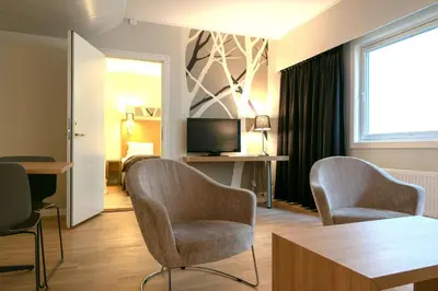 a living room with two chairs and a television at City Living Sentrum Hotel in Trondheim