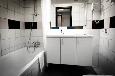 a bathroom with a sink and a tub and a mirror at Havila Hotel Geiranger in Geiranger