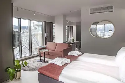 a bedroom with a bed and a couch and a window at Hotel Norge by Scandic in Bergen