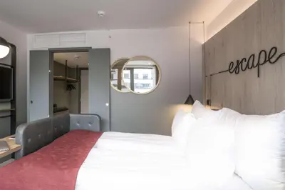 a bedroom with a large white bed and a mirror at Hotel Norge by Scandic in Bergen