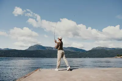 a man standing on a dock fishing on a lake at Ryfylke Fjordhotel in Sand