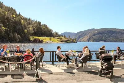 a group of people sitting at tables by a lake at Ryfylke Fjordhotel in Sand