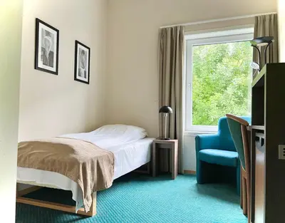 a bedroom with a bed and a chair and a window at Ryfylke Fjordhotel in Sand