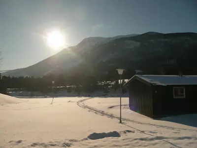 a building in the snow with the sun behind a mountain at Dovre Motell in Dovre
