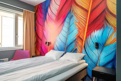 a bedroom with a bed with a colorful wall at Thon Hotel Storgata in Kristiansund