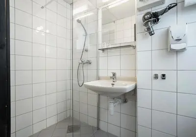a white bathroom with a sink and a shower at Thon Hotel Storgata in Kristiansund