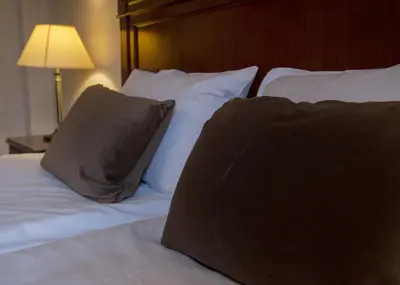 a bed with white pillows and a brown pillow on it at Fleischer's Hotel in Vossevangen