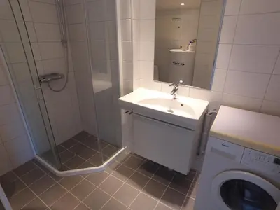a bathroom with a shower and a sink and a washing machine at Apartment Ulsteinvik in Ulsteinvik