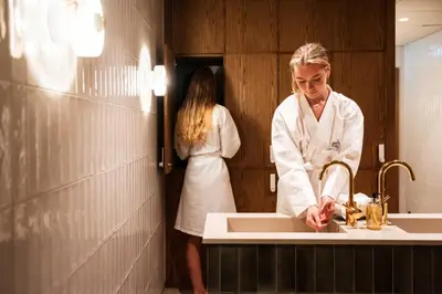 a woman standing in front of a sink in a bathroom at Sundvolden Hotel in Sundvollen