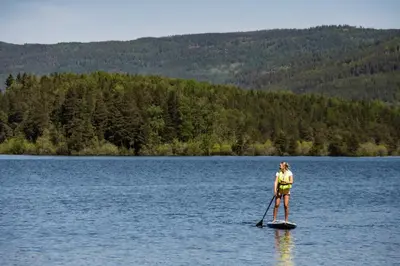 a person standing on a paddle board in a lake at Sundvolden Hotel in Sundvollen