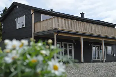 a black house with a balcony and some flowers at Nordseter Fjellpark, Hyttegrend in Nordseter