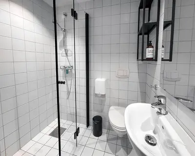 a bathroom with a shower and a toilet and a sink at Trolltunga Hotel in Odda