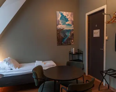 a room with a bed and a table and chairs at Trolltunga Hotel in Odda