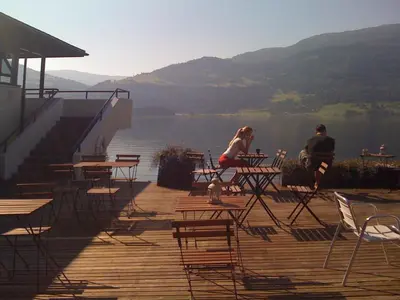 two people sitting at tables on a deck overlooking a lake at Voss Vandrarheim Hostel in Vossevangen