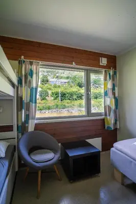 a bedroom with a bed and a chair and a window at Voss Vandrarheim Hostel in Vossevangen