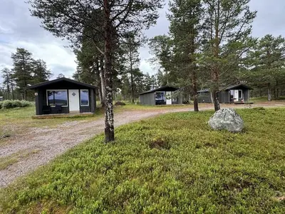 a cabin in the middle of a field with a tree at Femundtunet in Drevsjø