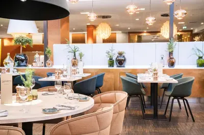 a restaurant with white tables and chairs and lights at Radisson Blu Royal Hotel, Bergen in Bergen