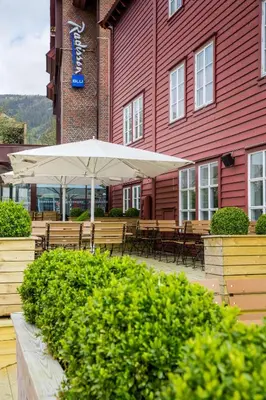 a patio with tables and umbrellas in front of a red building at Radisson Blu Royal Hotel, Bergen in Bergen