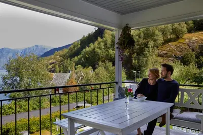 a man and a woman sitting at a table on a porch at Heimly Pensjonat in Flåm