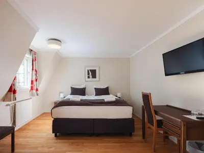 a bedroom with a bed and a desk and a television at Tyssedal Hotel in Tysso